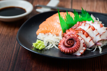 Tako sashimi and Salmon on black dish with chopsticks,