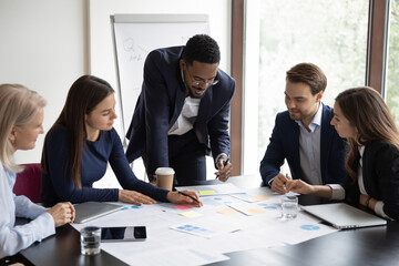 Multiethnic colleagues gather in boardroom brainstorm analyzing company financial paperwork...