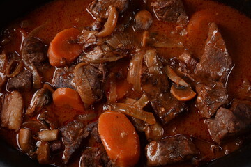 Beef Bourguignon in a pan. Stew with red wine ,carrots, onions, garlic, a bouquet garni, and garnished with pearl onions, mushrooms and bacon. French cuisine- regional recipe from Burgundy