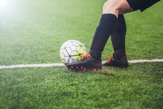 Close up photo of handed footballer legs kicking a ball on field