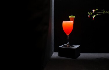 Red sparkling beverage, watermelon garnish, isolated against a black background