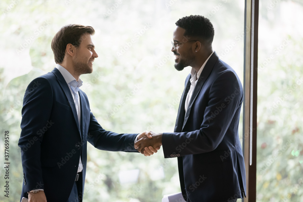 Canvas Prints Smiling multiracial businessmen shake hands get acquainted greeting at meeting in office. Happy diverse male colleagues or business partners handshake close deal make agreement. Partnership concept.