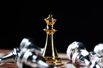 Gold queen chess defeats silver figures on board.
