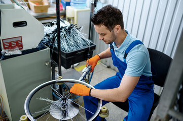 Worker with machine tool installs bicycle spokes