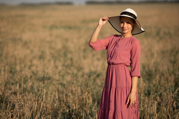beautiful young woman in hat in summer field