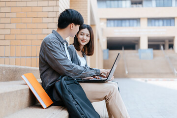  teenager sitting on stair at college campus with school books and a laptop computer doing homework. Education concept.