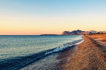 Sunrise, beach and wave in the early morning on the Mediterranean Sea. Greece.