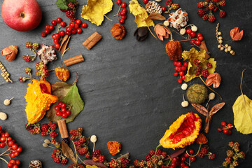 Dried flowers, leaves and berries arranged in shape of wreath on black background, flat lay with space for text. Autumnal aesthetic