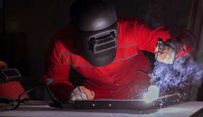 Fototapeta na wymiar Young repairman with a welding gun electrode and a helmet weldin