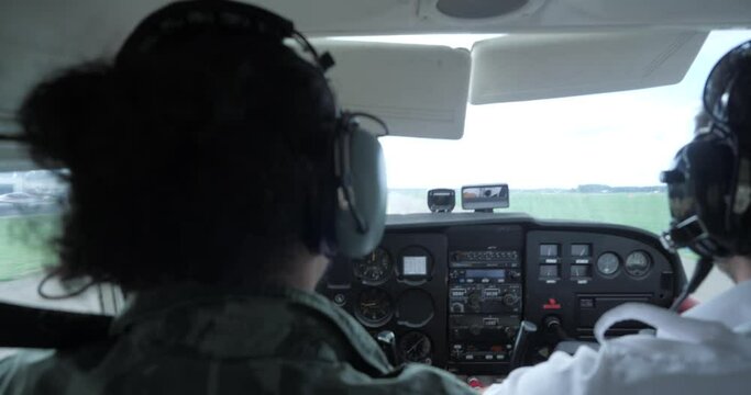 A slow motion shot of a uniformed pilot and copilot taking off. In the shot is the stick, radar and other aviation systems on the dashboard.