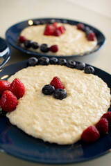 Oatmeal porridge with berries, in a blue plate. Healthy breakfast.