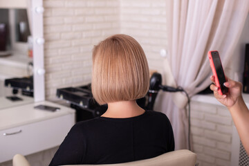 
Hairdresser hand taking photo of her client - woman with short blonde hairstyle - after haircut