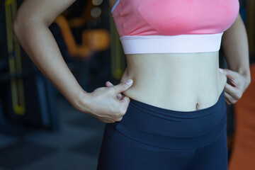 Close up portrait of fit woman checking fat on her side. Sports concept fat burning and a healthy lifestyle.