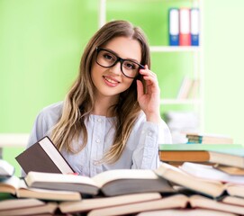 Young female student preparing for exams with many books