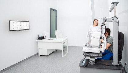 woman ophthalmologist with a man patient near ophthalmic equipment in a modern ophthalmological office. Eye diagnostic