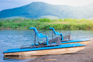 Walking catamaran with pedals for riding on water in the background of high mountains.