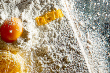 Freshly cooked pasta is lying on a dark surface dusted with flour. Italian pasta. Tagliatelle. Raw pasta. Italian pasta recipe. Top view, copy space