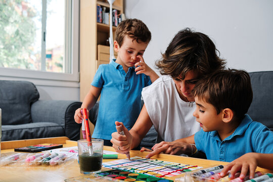 a mother helps her sons to draw and paint