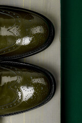 Green lacquered oxford shoes wooden background. Top view.