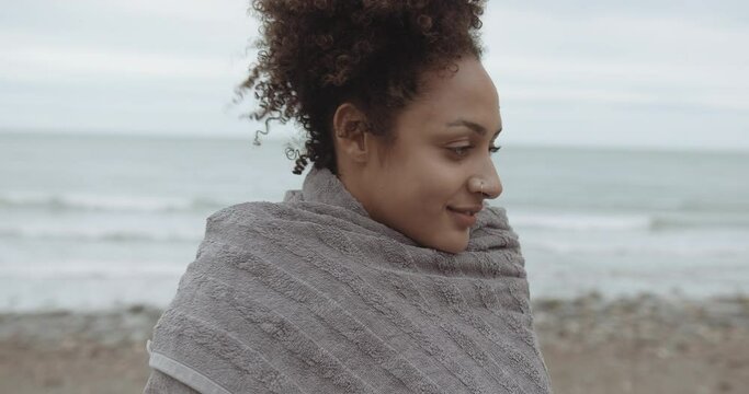 Close up of Pretty Afro Black female at the beach wrapped warm in towel after swim in sea