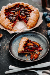  A piece of homemade plum pie on a black plate. Simple dessert with fruits, vertical photo