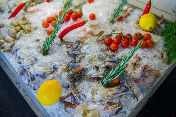 Fresh crabs displayed on ice with lemons, cherry tomatoes and thyme 