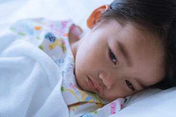 Asian cute little boy is lying sadly on the sickbed and the face with tears in the patient room in hospital. Healthcare medical and people concept.