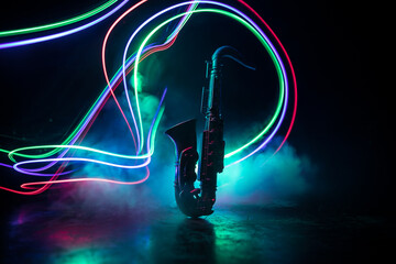 Alto gold sax miniature with colorful toned light on foggy background. Saxophone music instrument...