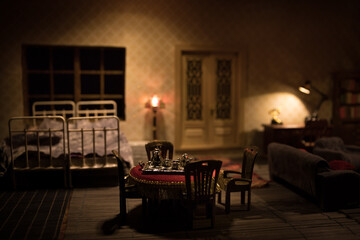 A realistic dollhouse living room with furniture and window at night. Artwork table decoration with handmade realistic dollhouse. Man wathing retro style Television in dark room.