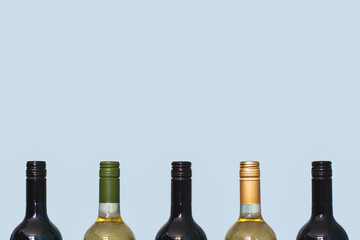 Tops of red and white wine bottles on light background. Space for text