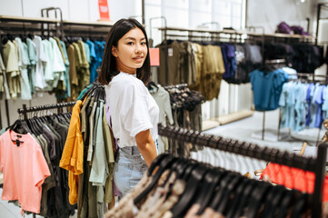 Naklejka na ściany i meble Woman choosing clothes in clothing store