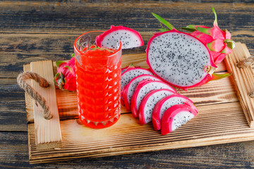 Dragon fruit in a tray with juice high angle view on a wooden background