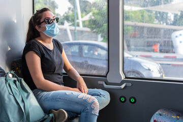 Girl wearing a mask preventing contagion sitting in a bus.
