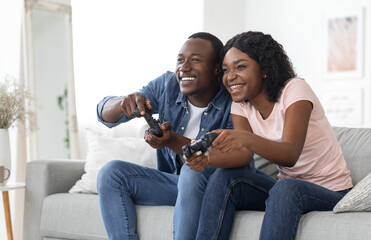 Emotional african couple playing video games at living room