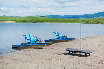 Walking catamarans with pedals for riding on water in the background of high mountains.