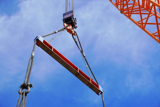 Crane is lifting the machine using spreader bar and sky background in a chemical factory.