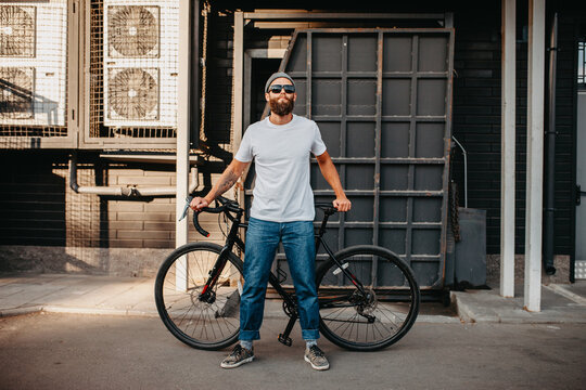 Young bearded hipster guy wearing white blank t-shirt with bicycle . Mock-up for print. T-shirt template.