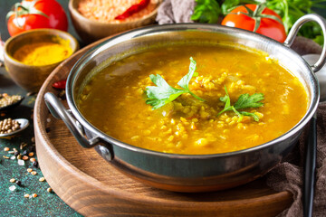 Indian cuisine. Traditional Indian spicy lentil puree soup with herbs on a dark background.