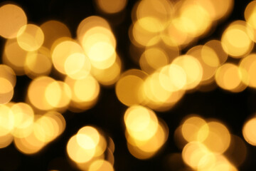 Obraz premium Defocused yellow lights are centered on a dark background.Christmas abstract bokeh texture background.The concept of the celebration or party