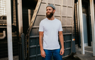 Young bearded hipster guy wearing white blank t-shirt. Mock-up for print. T-shirt template.