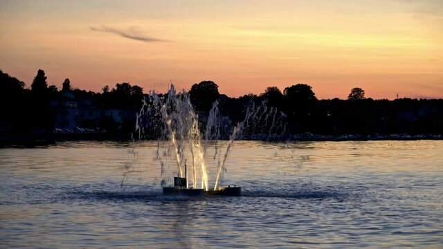 Sunset over the water in V&auml;stervik, Sweden, with a fountain turning off