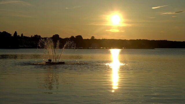 Sunset over the water in V&auml;stervik, Sweden, with a fountain