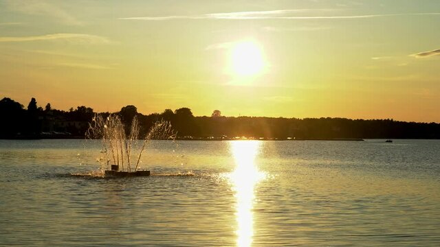 Sunset over the water in V&auml;stervik, Sweden, with a fountain turning off