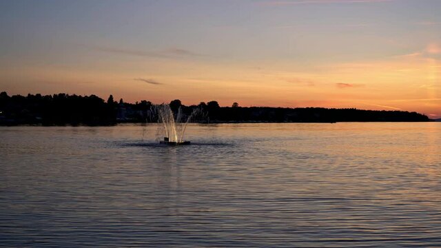 Sunset over the water in V&auml;stervik, Sweden, with a fountain