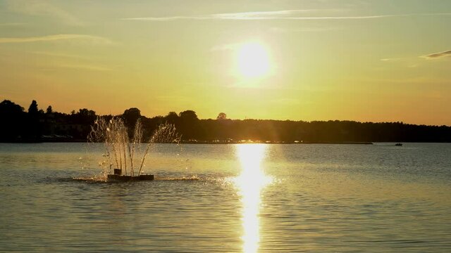 Sunset over the water in V&auml;stervik, Sweden, with a fountain turning off