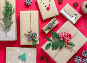 Christmas composition of gift boxes in craft paper on a red background.The concept of zero...