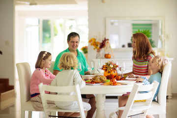 Family with kids at Thanksgiving dinner. Turkey.