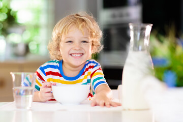 Child eating breakfast. Kid with milk and cereal.
