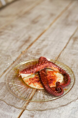 View of two roasted octopus legs with a base of mashed potatoes and paprika on a glass plate in a restaurant