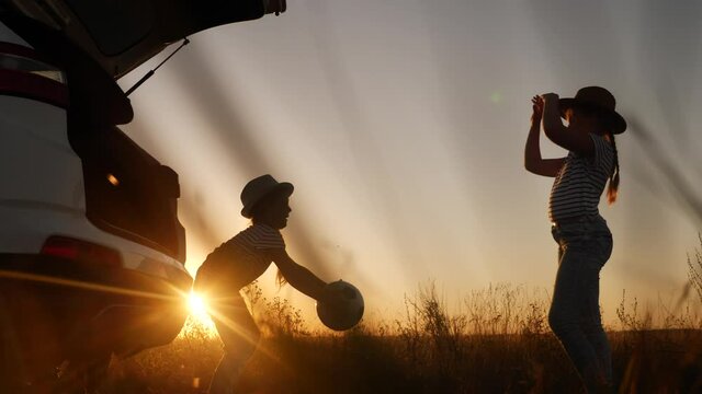 children in the park silhouette playing ball on vacation next to the car. happy family camping kid dream concept. two sisters kids throw a ball each other play silhouette. girl kid dream fun